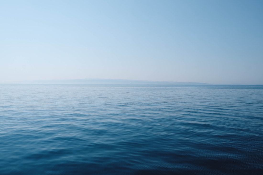 Calm ocean under a blue and white sky