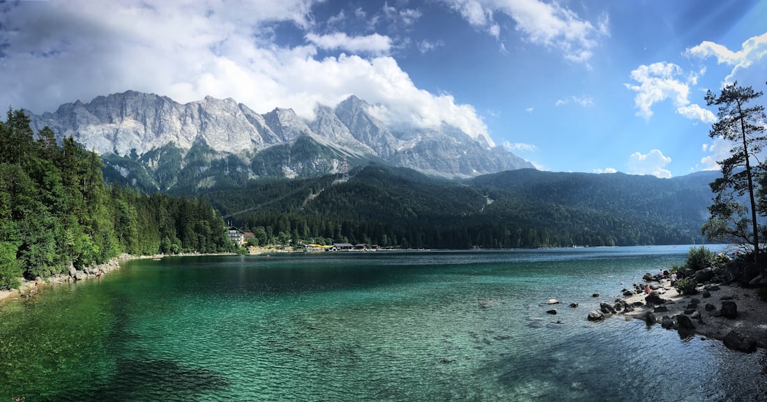 Lake surrounded by trees and mountains under clouds